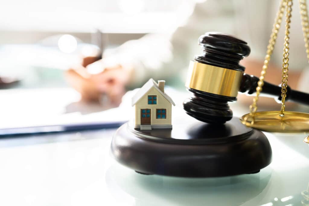 Model of Huntington Beach home with a gavel and scale in California law office.